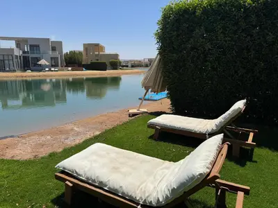 two chairs and an umbrella next to a body of water at NEXT STAY, Lagoon Townhouse, El Gouna in Hurghada