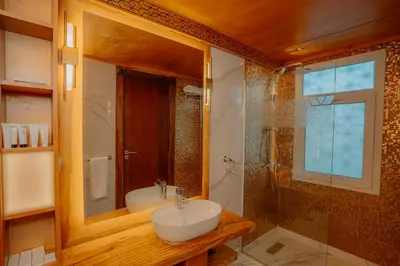 a bathroom with a sink and a glass shower at Azhar Dahabiya luxury suites in Esna
