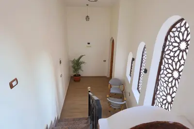 a hallway with white walls and a staircase with chairs at Golden Land in ‘Ezbet Abu Ḥabashi