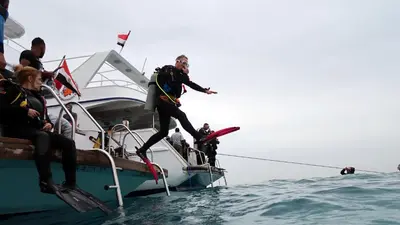a man jumping off of a boat in the water at Funnydivers Diving center in Hurghada