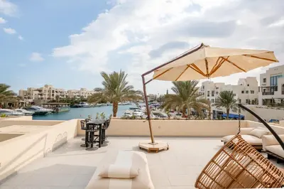 a patio with chairs and an umbrella and a view of the water at Elegant Fanadir Marina 2BR • Ground Floor in Hurghada