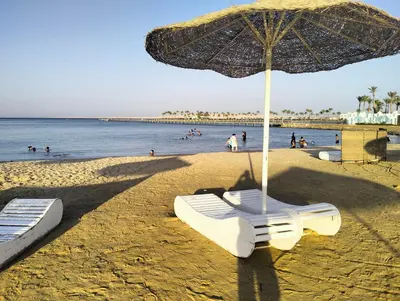 a beach with two lounge chairs and an umbrella at Scandic Resort Hurghada in Hurghada