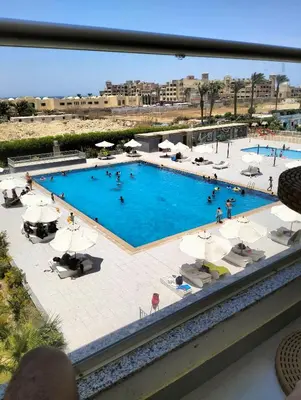 a large swimming pool with people sitting around it at Scandic Resort Hurghada in Hurghada