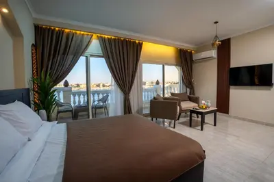 a hotel room with a bed and a balcony at Nile Crown Luxor in Luxor