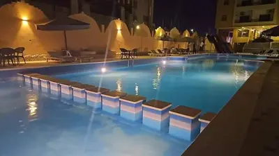 a swimming pool at night with chairs around it at كومباوند فوكس هاوس in Hurghada
