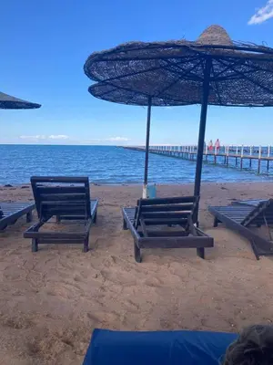 a group of chairs and an umbrella on a beach at كومباوند فوكس هاوس in Hurghada