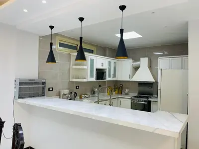 a kitchen with white cabinets and black pendant lights at Comfortable & Modern Appartement in Luxor