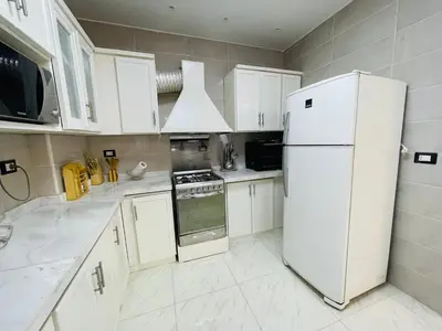 a kitchen with white cabinets and a white refrigerator at Comfortable & Modern Appartement in Luxor