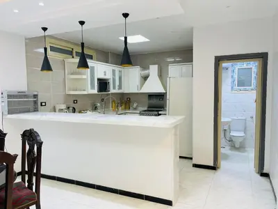 a kitchen with white cabinets and a white counter top at Comfortable & Modern Appartement in Luxor