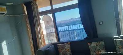 a living room with a couch and a large window at شقة كورنيش النيل 3غرف فيو كامل علي النيل in Aswan