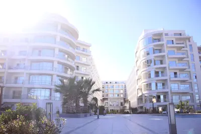 two tall white buildings with palm trees in front of them at Luxury serviced apartments in Hurghada