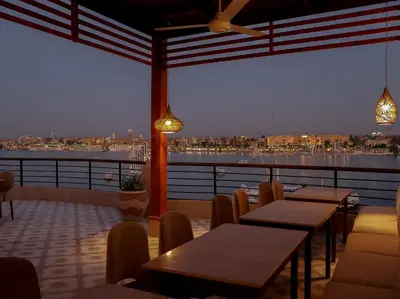 a restaurant with tables and chairs and a view of the water at Boutique hotel Neferu Stay in Luxor