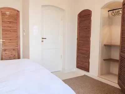 a bedroom with white walls and wooden doors at Boutique hotel Neferu Stay in Luxor