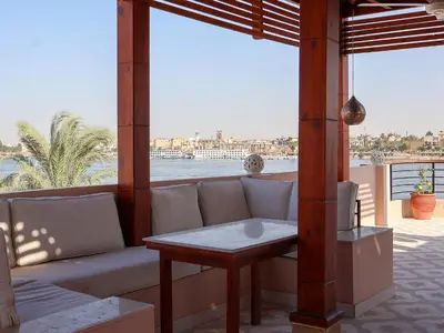 a couch on a porch with a view of the water at Boutique hotel Neferu Stay in Luxor