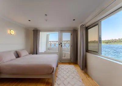 a bedroom with a bed and a large window at Anoush Dahabiya 4 nights from Luxor to Aswan each Monday in Luxor
