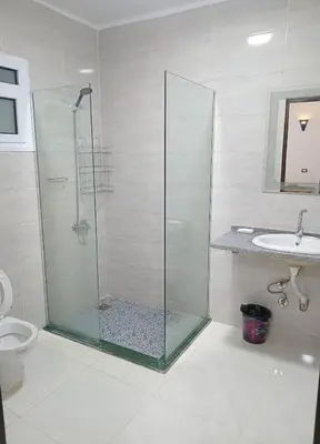 a bathroom with a glass shower and a sink at Maat Studio in Luxor