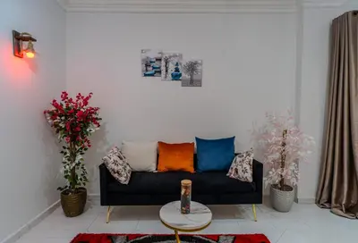 a living room with a black couch with colorful pillows at Madares sweet home appartment in Hurghada