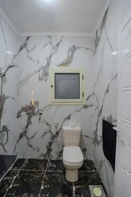 a bathroom with a toilet and a tv on the wall at Madares sweet home appartment in Hurghada
