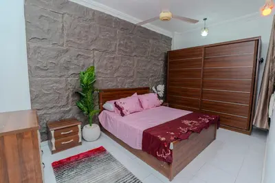 a bedroom with a pink bed and a stone wall at Madares sweet home appartment in Hurghada
