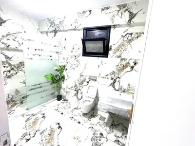 a bathroom with a toilet and a marble wall at Mohamed Home in Jazīrat al ‘Awwāmīyah