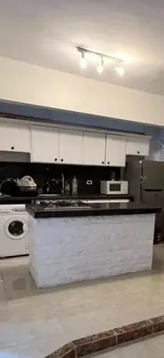 a kitchen with white cabinets and a counter top at Mohamed Home in Jazīrat al ‘Awwāmīyah