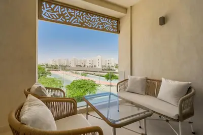 a living room with a table and chairs and a large window at Glow & Tide 1BDR w Rooftop Mangroovy Free Pool & Beach Access in Hurghada