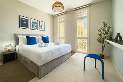 a bedroom with a large bed and a blue stool at Glow & Tide 1BDR w Rooftop Mangroovy Free Pool & Beach Access in Hurghada