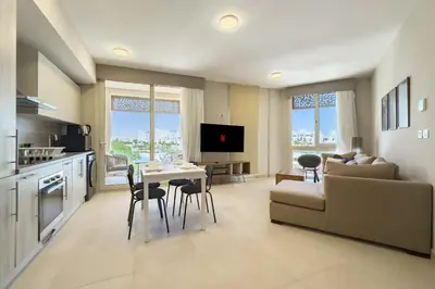 a kitchen and living room with a couch and a table at Glow & Tide 1BDR w Rooftop Mangroovy Free Pool & Beach Access in Hurghada
