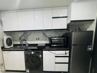 a kitchen with white cabinets and a microwave at Modern loft overlooking downtown in Scandic Resort in Hurghada