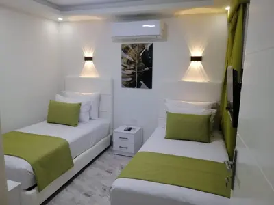 two beds in a white room with green pillows at Selena Bay Resort in Hurghada