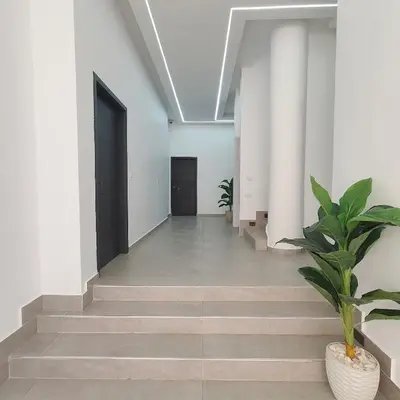 a hallway with white walls and stairs with a plant at Arabic Apartment in Hurghada