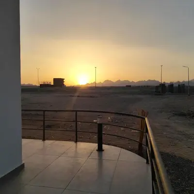 a sunset in the middle of a desert with a fence at Boho Apartment in Hurghada