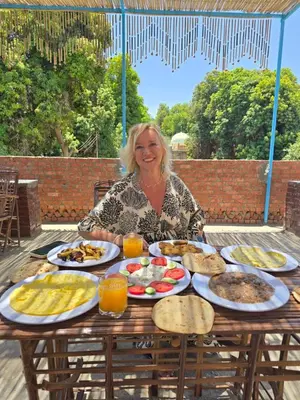 a woman sitting at a table full of food at Garden view in Aswan
