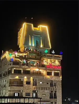 a building with lights on top of it at night at El Massa in Idfu