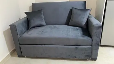 a grey couch with two pillows on top of it at Zafira Apartman in Hurghada
