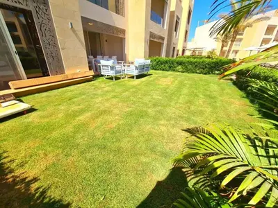 a lawn in front of a building with chairs on it at Apartment in El gouna mangrouovy in Hurghada
