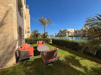 a patio with chairs and a table next to a pool at Apartment in front of the beach in Hurghada