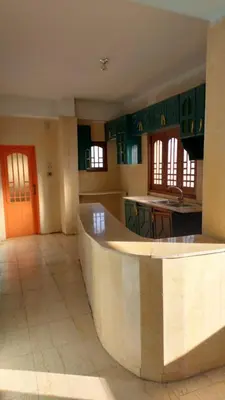 a large kitchen with green cabinets and a large island at Downtown apartment in Luxor