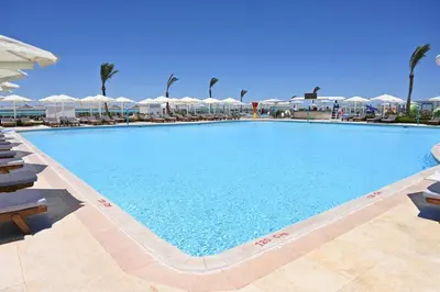 a large swimming pool with chairs and umbrellas at Riviera Aqua Park Resort in Hurghada