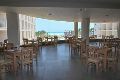 a restaurant with tables and chairs and a view of the ocean at Riviera Aqua Park Resort in Hurghada