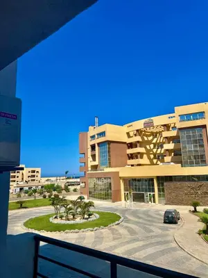 a building with a car parked in a parking lot at Apartment with private beach 09E in Hurghada