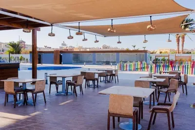 an outdoor patio with tables and chairs and a pool at شالية منتجع سكانديك عرابيا in Hurghada