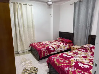 two beds in a room with red sheets and curtains at apartment in Hurghada