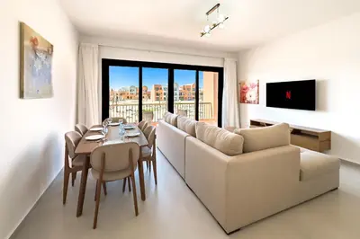 a living room with a couch and a table with chairs at Cool & Curated 1BDR Kamaran El Gouna in Hurghada