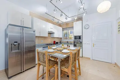 a kitchen with a table and a stainless steel refrigerator at Townhouse South Marina in Hurghada