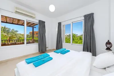 a bedroom with a white bed and two windows at Townhouse South Marina in Hurghada
