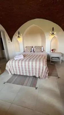 a bedroom with a bed and two tables in a room at Lady of the Sun Guesthouse in Luxor