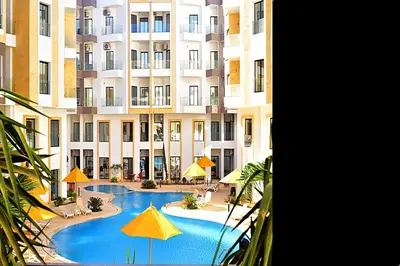 a large building with a swimming pool with yellow umbrellas at One bedroom apartment with a hall in Aqua Infinity Resort before El Gouna in Hurghada