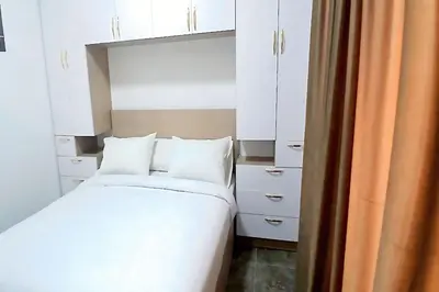 a bedroom with a bed with white cabinets and an orange curtain at One bedroom apartment with a hall in Aqua Infinity Resort before El Gouna in Hurghada