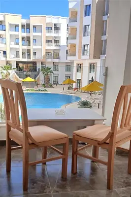 two chairs and a table and a swimming pool at One bedroom apartment with a hall in Aqua Infinity Resort before El Gouna in Hurghada